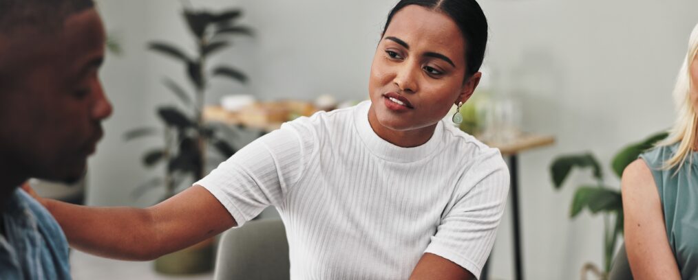 Woman comforts individual during group therapy session.